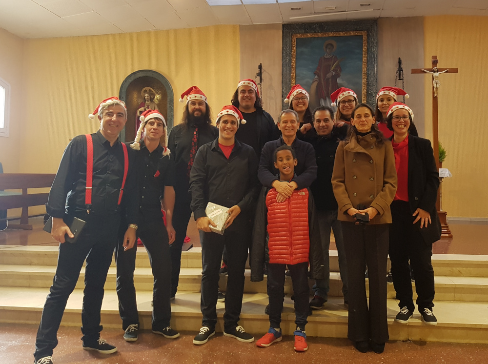 Foto de grup d'En Clau Vocal a l'interior de la Parròquia de Sant Fèlix, amb barrets de Pare Noel, davant de l'altar.