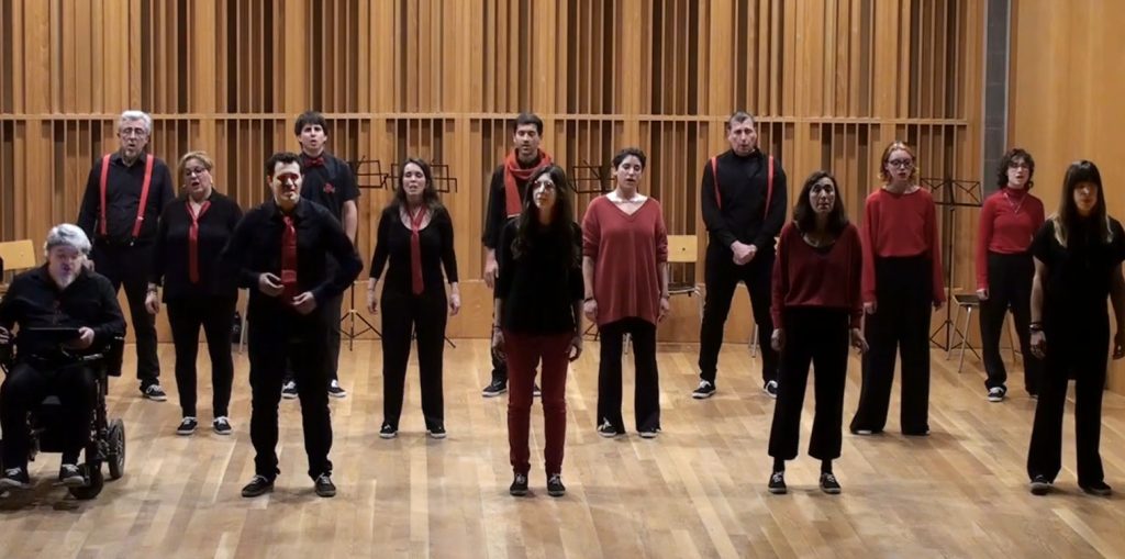 Els cantaires d'En Clau Vocal, de negre i vermell, drets a l'escenari de fusta de l'Auditori del Palau Falguera.